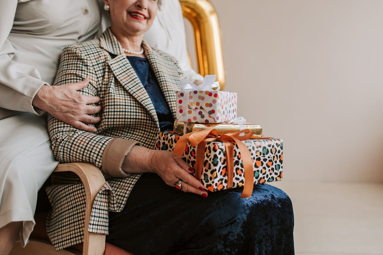Senior woman receives gifts during indoor celebration with family support.